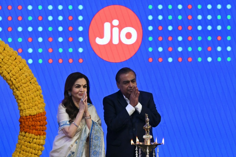 Le milliardaire indien et président de Reliance Industries, Mukesh Ambani (d), et son épouse Nita Ambani, saluent l'assistance lors de l'introduction en bourse de Jio Platforms à la Bourse de Bombay, le 28 octobre 2026 en Inde