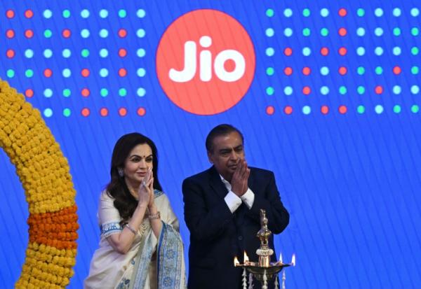 Le milliardaire indien et président de Reliance Industries, Mukesh Ambani (d), et son épouse Nita Ambani, saluent l'assistance lors de l'introduction en bourse de Jio Platforms à la Bourse de Bombay, le 28 octobre 2026 en Inde