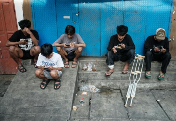 Des enfants utilisent leur smartphone à Jakarta le 26 mars 2026.