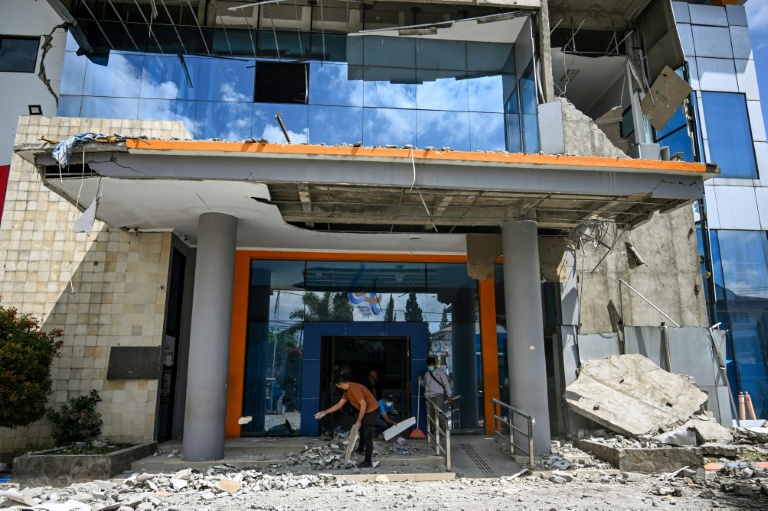 Des employés ramassent des gravats devant une banque après le puissant séisme qui a secoué l'île indonésienne de Florès, dans l'est de l'archipel, le 16 août 2026 à Ruteng, à quelque 158 kilomètres à l'ouest de l'épicentre 