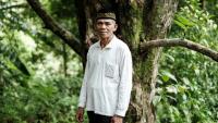Jauhar Mahmud, cultivateur de clous de girofle, devant son giroflier préféré, âgé de 60 ans, l'un des 150 qu'il possède, sur l'île de Ternate, le 11 avril 2025 en Indonésie
