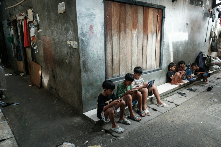 Des enfants jouent sur des téléphones et tablettes à Jakarta, en Indonésie, le 26 mars 2026