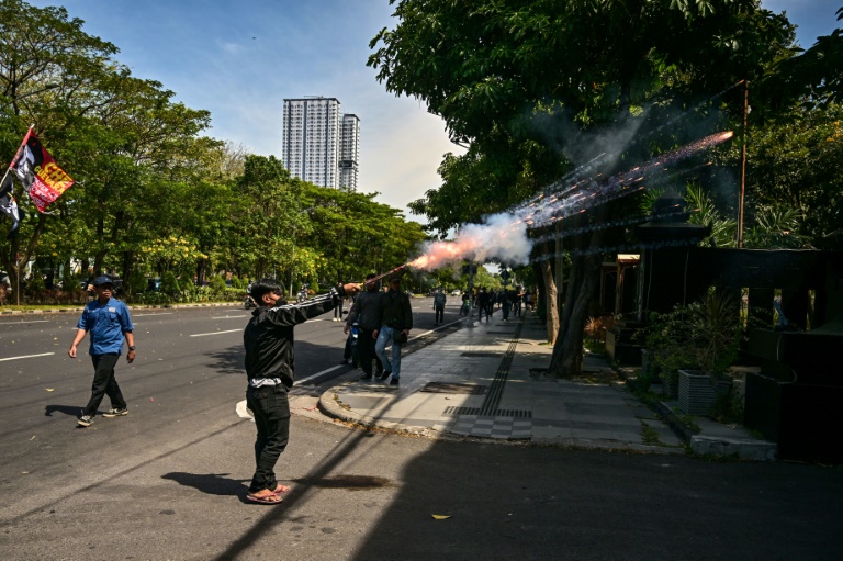 Un manifestant tire un mortier d'artifice en direction de la police lors d'une manifestation après la mort d'un taxi-moto écrasé par un véhicule de police, le 30 août 2025 à Surabaya, sur l'île indonésienne de Java