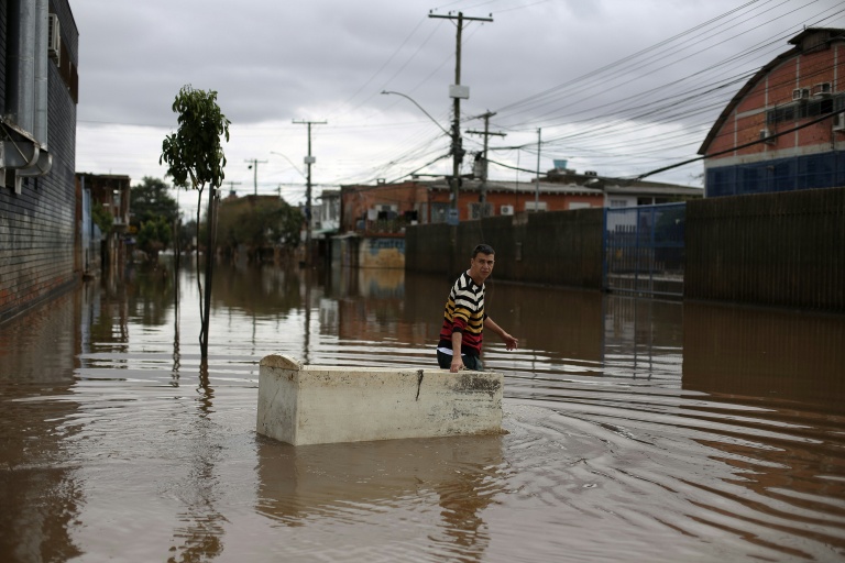 Un habitant utilise un réfrigérateur endommagé comme embarcation pour transporter des provisions dans une rue inondée de Porto Alegre, dans l'État de Rio Grande do Sul, au Brésil, le 26 mai 2024, pendant des inondations historiques dans le pays