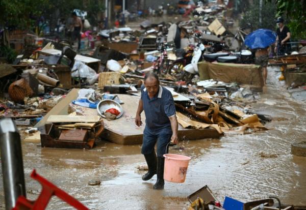 Un habitant récupère de l'eau de pluie dans une zone inondée après la rupture d'un réservoir près de Gantang, dans la région du Guangxi, le 9 juillet 2026 dans le sud-ouest de la Chine