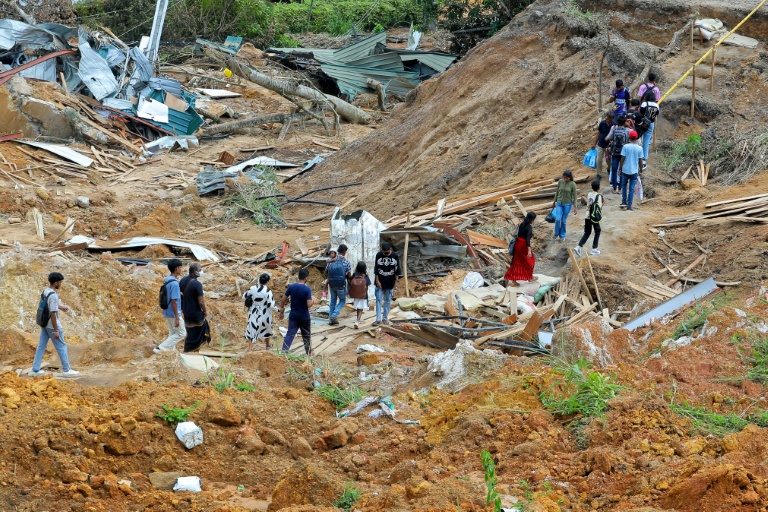 Des habitants au milieu d'arbres déracinés et de maisons endommagées après des glissements de terrain provoqués par le cyclone Ditwah dans le village d'Ulapane, près de la ville de Nawalapitiya, dans le district de Kandy, le 7 décembre 2025 au Sri Lanka