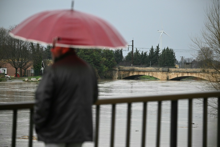 Un passant observe le débordement de l'Aude après des fortes pluies à Coursan, le 19 janvier 2026 dans l'Aude