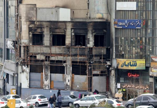 Des passants le 19 janvier 2026 devant un immeuble détruit lors des manifestations à Téhéran, en Iran