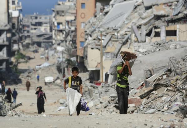 Des enfants portent du bois parmi les décombres dans le camp palestinien de Al-Shatee, dans l'est de la bande de Gaza, le 8 novembre 2025