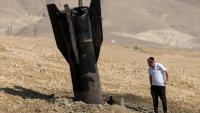 Un Israélien inspecte une roquette tombée, à moitié enfouie dans le sol, en périphérie de Jéricho en Cisjordanie, le 8 juin 2026.