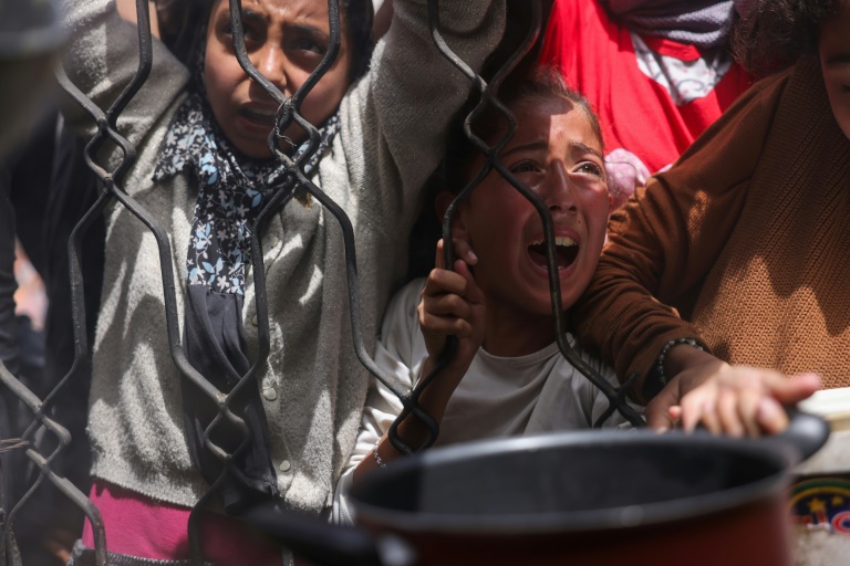 Des enfants palestiniens se bousculent pour obtenir un repas d'une cuisine caritative à Jabalia, dans le nord de la bande de Gaza, le 17 mai 2025