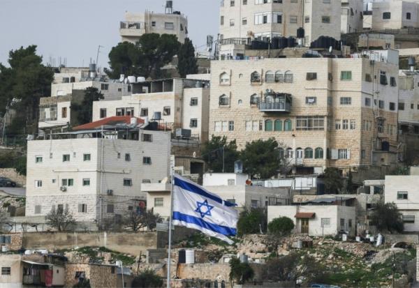 Un drapeau israélien flottant du dessus d'une colonie israélienne, devant des habitations palestiniennes d'Hébron, en Cisjordanie, le 9 février 2026