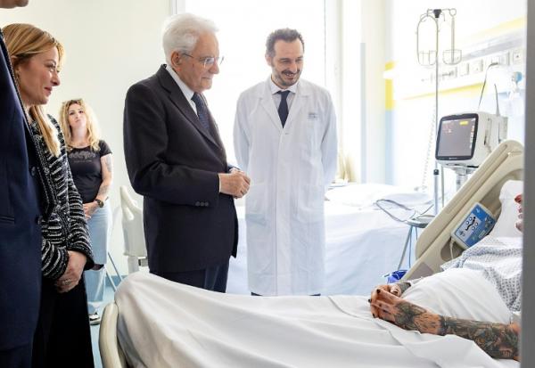 Photo publiée par les services de la présidence italienne montrant le président Sergio Mattarella (C) et la présidente du Conseil Giorgia Meloni (G) au chevet d'une des victimes renversées par un conducteur ayant des antécédents psychiatriques, le 17 mai 2026 à Modène
