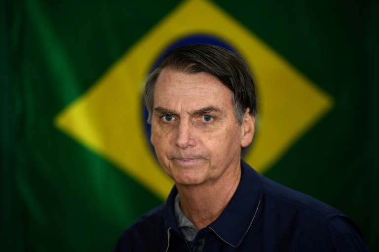 Jair Bolsonaro passe devant un drapeau brésilien dans un bureau de vote de Rio de Janeiro le jour de l'élection présidentielle, le 7 octobre 2018