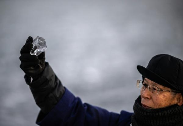 Kiyoshi Miyasaka, prêtre japonais du culte shinto, brandit un morceau de glace du lac Suwa, le 29 janvier 2026 dans la préfecture de Nagano, dans le centre de l'archipel 
