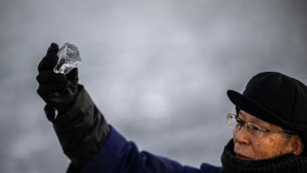 Kiyoshi Miyasaka, prêtre japonais du culte shinto, brandit un morceau de glace du lac Suwa, le 29 janvier 2026 dans la préfecture de Nagano, dans le centre de l'archipel 