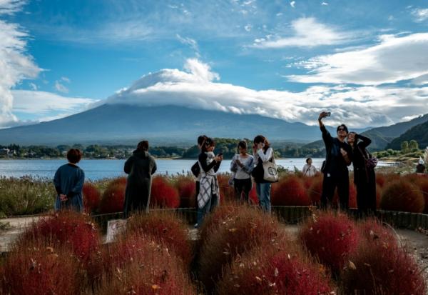 Des touristes prennent des photos devant le Mont Fuji, le 18 octobre 2025 à Fujikawaguchiko, au Japon