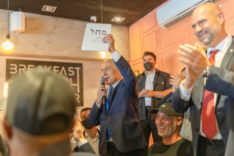 Le Premier ministre israélien Benjamin Netanyahu (d) s'adresse à ses sympathisants dans un café à Dimona, le 21 octobre 2026 en Israël