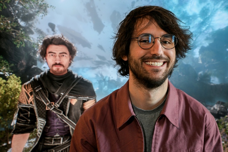 Le fondateur et directeur créatif de Sandfall Interactive, Guillaume Broche, pose devant une image d'un personnage de 