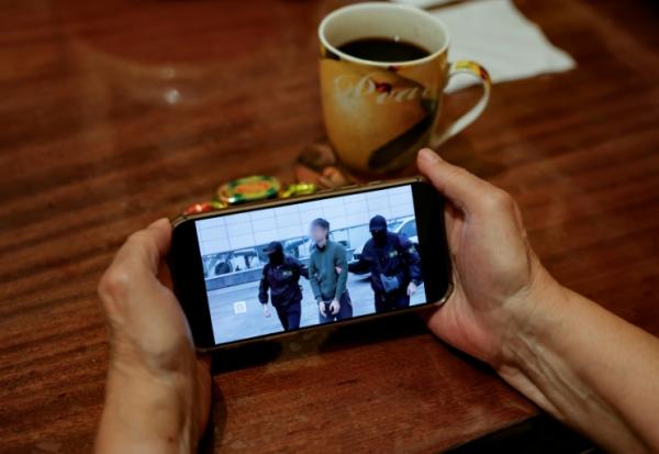 Une personne regarde sur un smartphone un fil d'actualité diffusant des images du FSB russe montrant l'opération d'interpellation d'un journaliste japonais accusé d'espionnage, à Moscou, le 13 octobre 2026