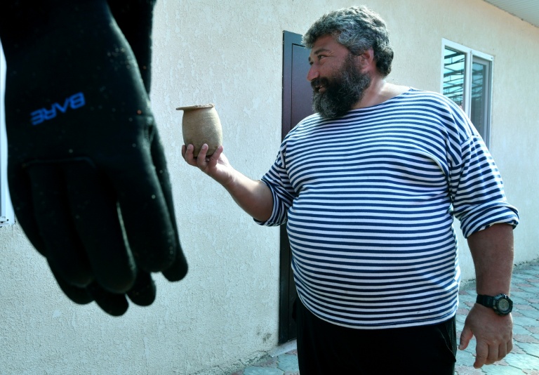 Maxime Menchikov, archéologue et directeur de l'expédition, tient des artefacts découverts sur le site sous-marin du fond du lac Issyk-Koul, près de la localité de Torou-Aïguyr au Kirghizistan, le 22 septembre 2026