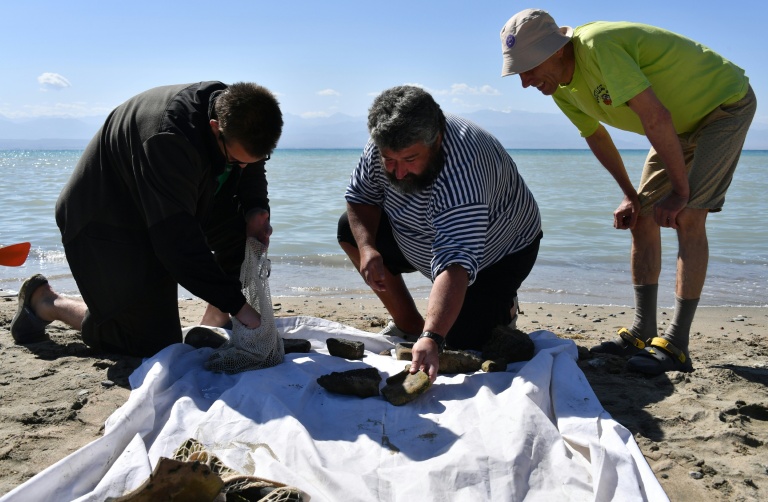 Maxime Menchikov et ses collègues examinent les objets découverts par des plongeurs au fond du lac Issyk-Koul, le 22 septembre 2026, près de  Torou-Aïguyr, au Kirghizstan
