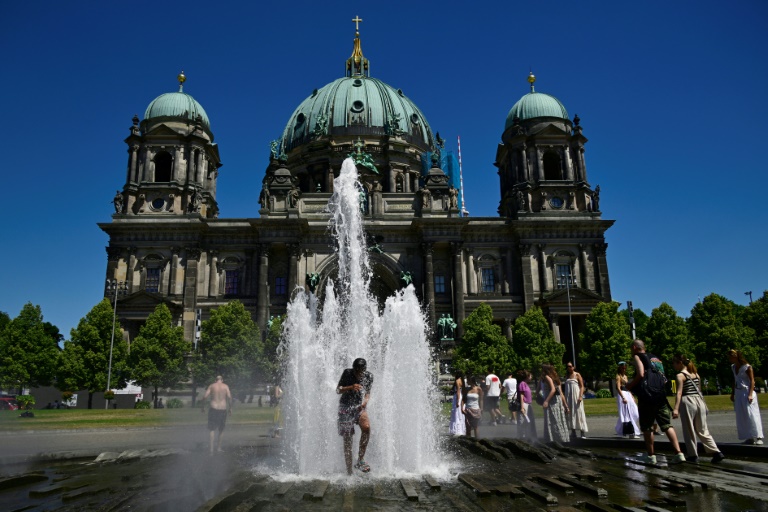Des personnes se rafraîchissent dans l'eau d'une fontaine, le 2 juillet 2025 à Berlin