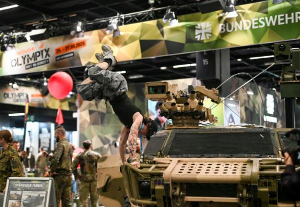 Un visiteur fait le poirier sur un véhicule de l'armée allemande, sur le stand de la Bundeswehr, au plus grand salon mondial du fitness, la Fibo, à Cologne (ouest de l'Allemagne), le 16 avril 