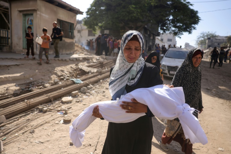 Une Palestinienne porte le corps d'un enfant tué dans une frappe, enveloppé dans un linceul blanc à l'extérieur de l'hôpital al Chifa de Gaza-ville, le 29 août 2025