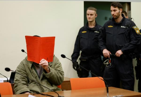 L'Afghan Farhad N. (g.), le visage caché derrière un dossier, est assis dans la salle d'audience du tribunal, le 16 janvier 2026 à Munich, pour le début de son procès pour avoir foncé en voiture dans la foule à Munich en 2025