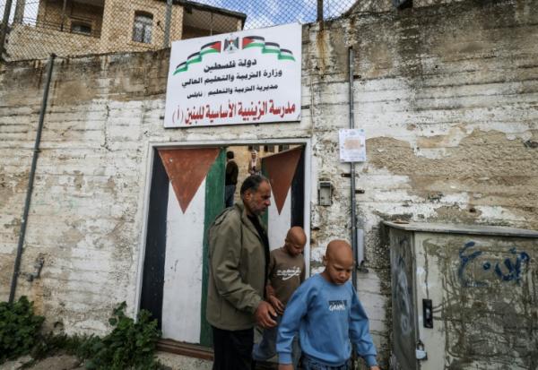 Les jumeaux Ahmad (d) et Mohammad, accompagnés par leur père Ibrahim al-Hajj, sortent de leur école à Naplouse, le 10 février 2026 en Cisjordanie occupée