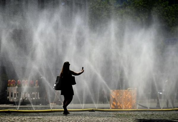 Une femme prend une photo de tuyaux d'arrosage déversant de l'eau pour apporter un peu de fraîcheur face à la chaleur estivale, à Cologne, dans l'ouest de l'Allemagne, le 25 juin 2026