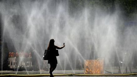 Une femme prend une photo de tuyaux d'arrosage déversant de l'eau pour apporter un peu de fraîcheur face à la chaleur estivale, à Cologne, dans l'ouest de l'Allemagne, le 25 juin 2026