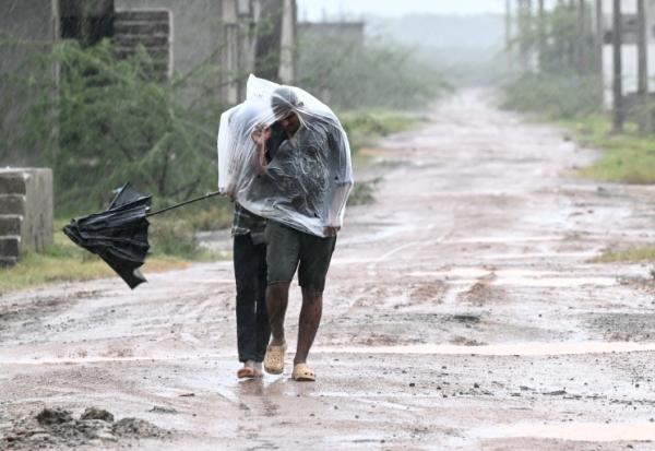 Des habitants se protègent de la pluie et du vent à Kakinada en Inde le 27 octobre 2026 avant l'arrivée du cyclone Arnab