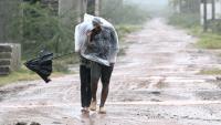 Des habitants se protègent de la pluie et du vent à Kakinada en Inde le 27 octobre 2026 avant l'arrivée du cyclone Arnab