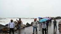 Des passants le long de la côte du golfe du Bengale, à Kakinada, en Inde, le 27 octobre 2026, avant le passage attendu du cyclone Arnab