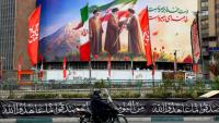 Un motocycliste passe devant un panneau représentant les trois guides suprêmes iraniens, le 10 mars 2026 à Téhéran