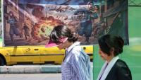 Des Iraniennes passent devant une affiche représentant les frappes israélo-américaines contre l'Iran, le 9 mai 2026 à Téhéran 