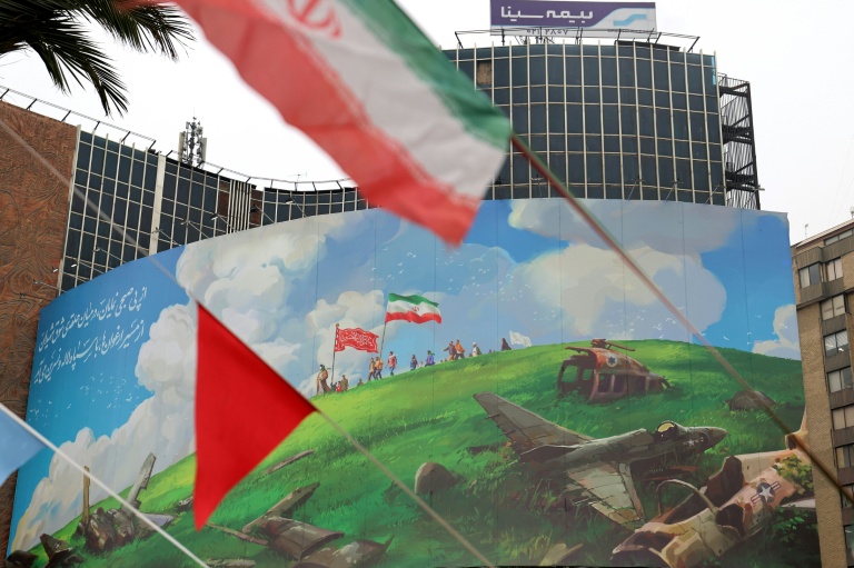 Dans le centre de Téhéran, le drapeau iranien flotte devant un vaste panneau anti-américain, le 8 février 2026