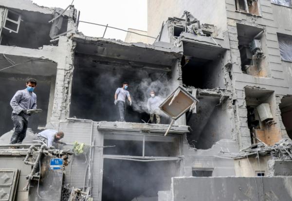 Des Iraniens dégagent les décombres de maisons détruites par des frappes israélo-américaines, le 15 mars 2026 à Téhéran