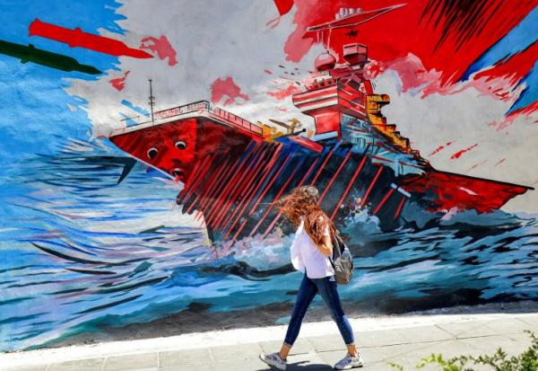 Une femme passe devant une peinture murale anti-américaine et anti-israélienne, le 26 mai 2026 à Téhéran