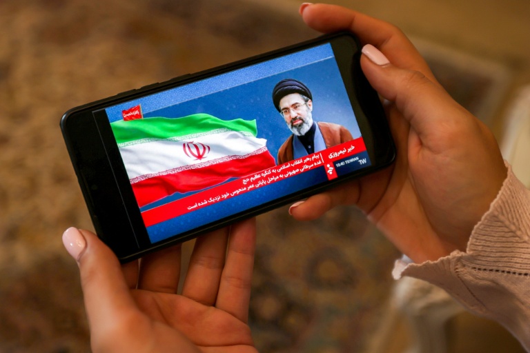 Une femme consulte sur son mobile un message du guide suprême iranien Mojtaba Khamenei, le 26 mai 2026 à Téhéran