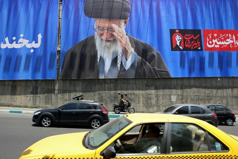 Des automobilistes passent devant un panneau géant sur lequel figure une photo de l'ayatollah Ali Khamenei, le défunt guide suprême de l'Iran, le 2 juillet 2026 à Téhéran, à la veille de ses funérailles