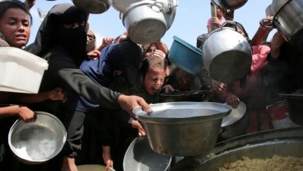 Des femmes et des enfants palestiniens tendent leurs casseroles vides devant une cuisine communautaire à Khan Younes, dans le sud de la bande de Gaza, le 21 août 2025
