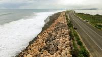 Vue aérienne montrant les vagues qui s’écrasent contre la digue protégeant la route vers l’aéroport international de Kingston en Jamaïque, le 25 octobre 2025, à l'approche de l'ouragan Melissa.