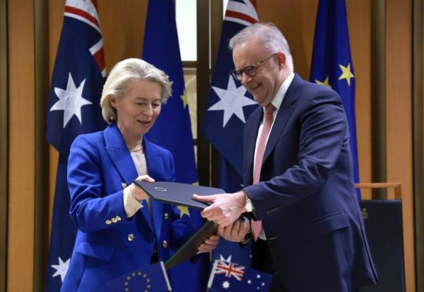 La présidente de la Commission européenne Ursula von der Leyen et le Premier ministre australien Anthony Albanese échangent des copies de l'accord commercial Australie-UE, le 24 mars 2026 à Canberra