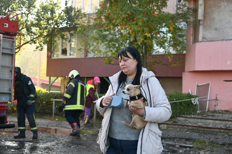 Une femme avec son chien devant un bâtiment touché par une attaque russe à Kharkiv, Ukraine, le 12 octobre 2026