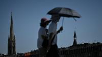 Des passants se protègent du soleil avec un parapluie à Bordeaux, le 5 juillet 2026 en Gironde, lors d'une vague de chaleur en France