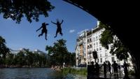 Des jeunes sautent d'un pont dans le canal Saint-Martin lors d'une vague de chaleur à Paris, le 22 juin 2026