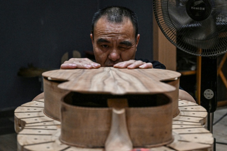 Cette photo prise le 27 juillet 2026 montre un ouvrier fabriquant une guitare dans un atelier de lutherie à Zheng'an, dans la province du Guizhou, dans le sud-ouest de la Chine.